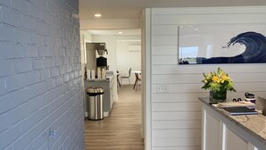 A modern kitchen with a brick wall, wooden flooring, and a kitchen island with a vase of flowers. - Breakwater Hotel (Provincetown)
