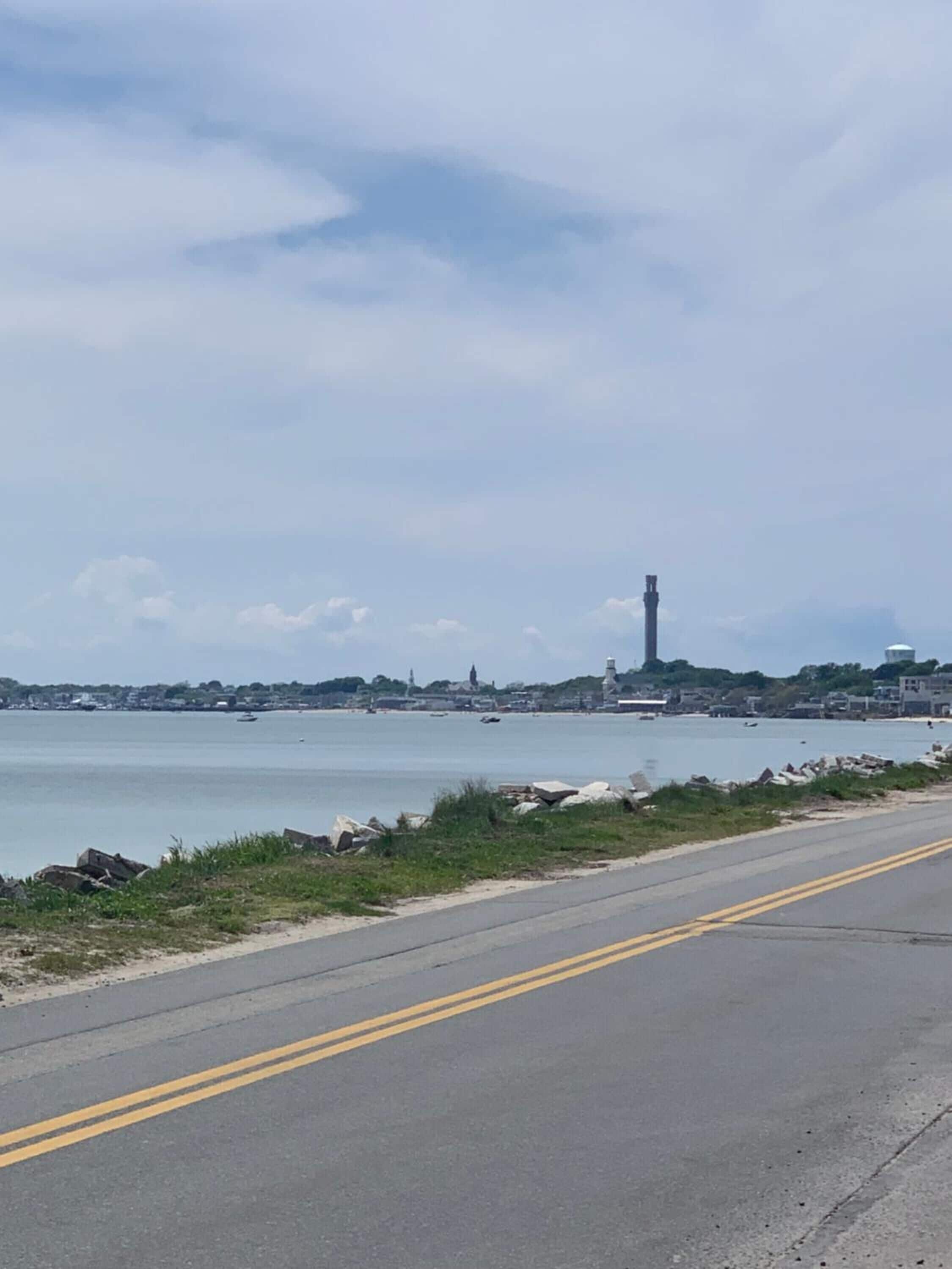 A coastal road with a clear view of the sea and distant buildings.