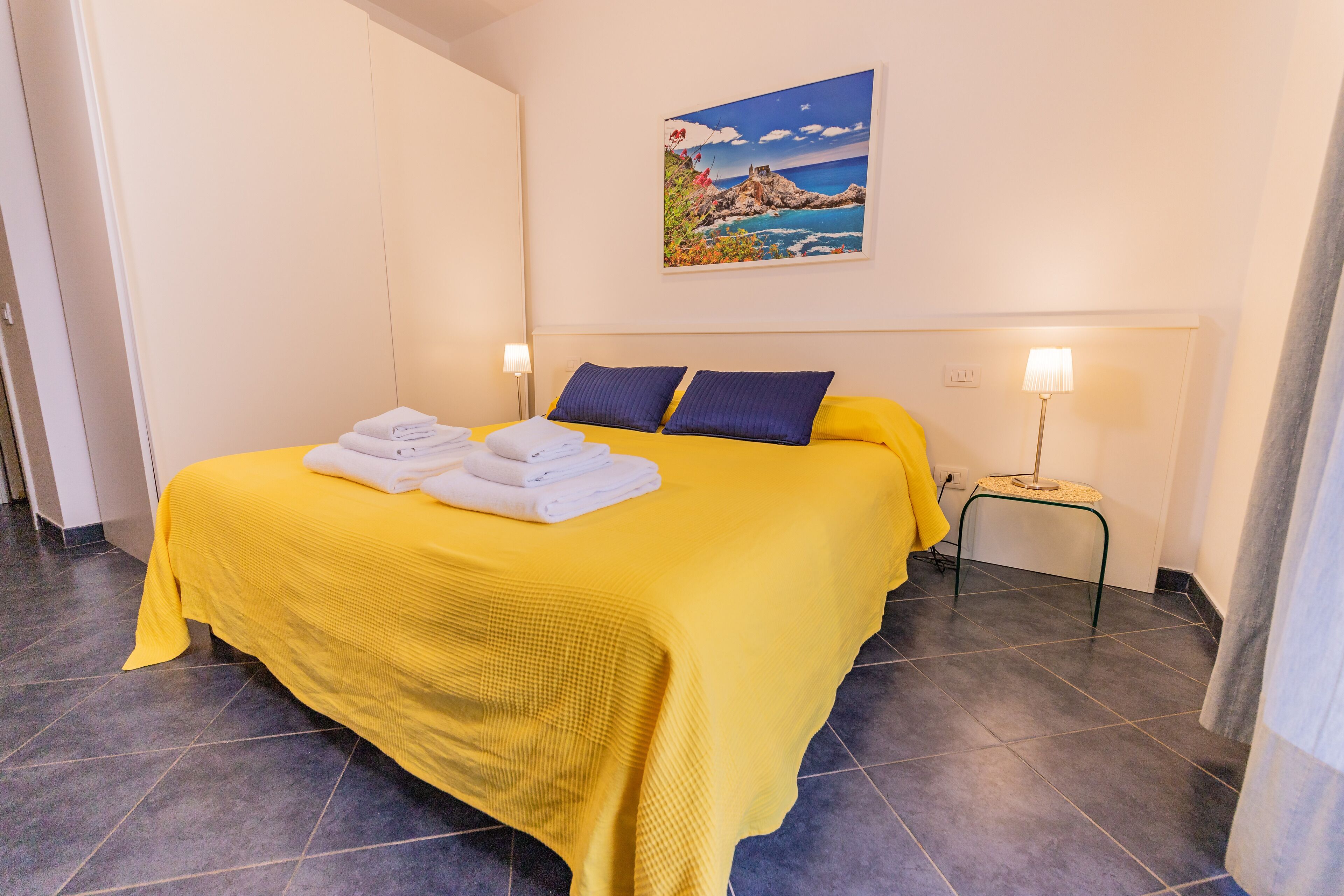 Une chambre d’hôtel avec un grand lit, un tableau au mur et une table de chevet avec une lampe.
