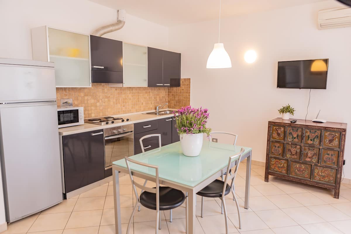 Una cocina moderna con una mesa de comedor de vidrio, electrodomésticos de acero inoxidable y un mueble decorativo.