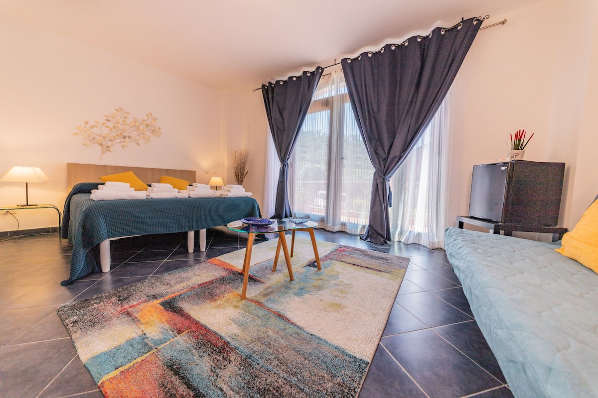 Una habitación de hotel con una cama, un sofá, un televisor y una mesa con lámpara.