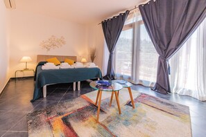 A bedroom with a bed, bedside lamps, a glass table, and a colorful rug.