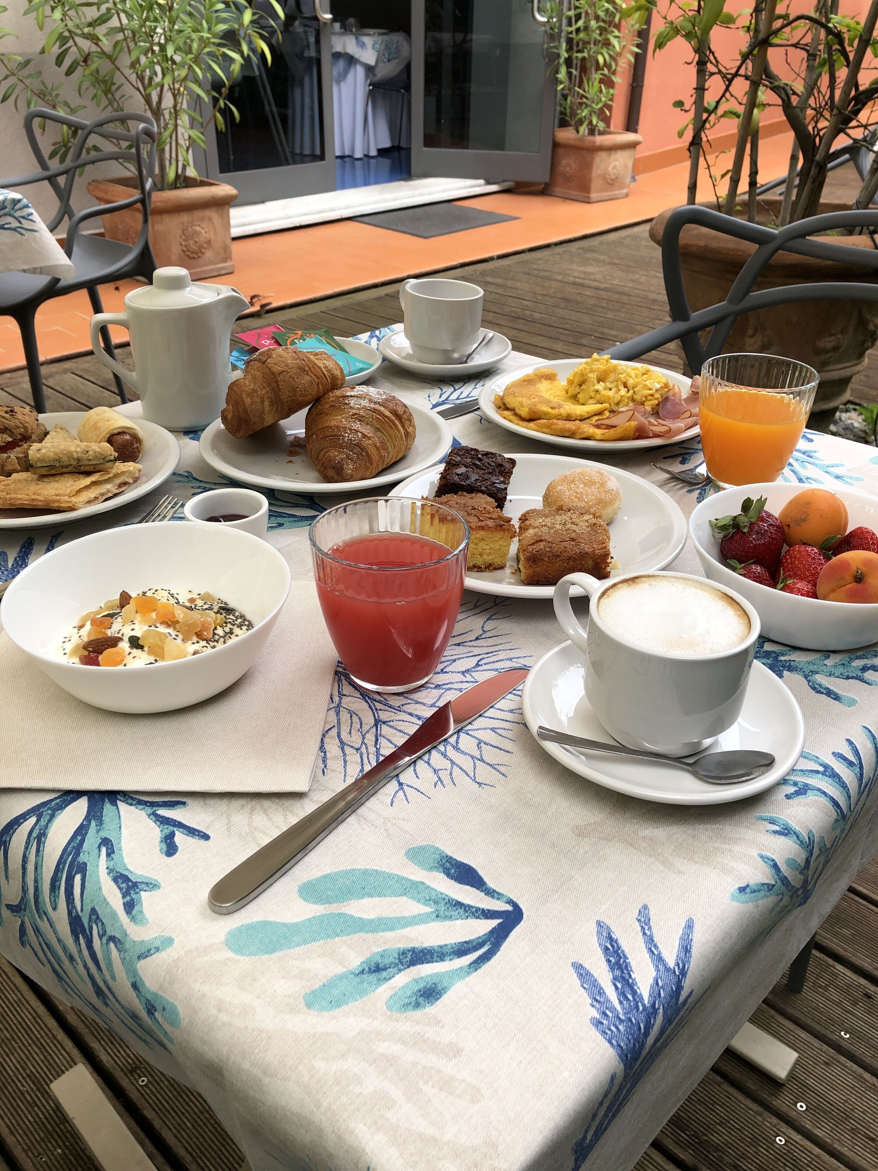 A table set with breakfast items including croissants, fruit, and coffee.