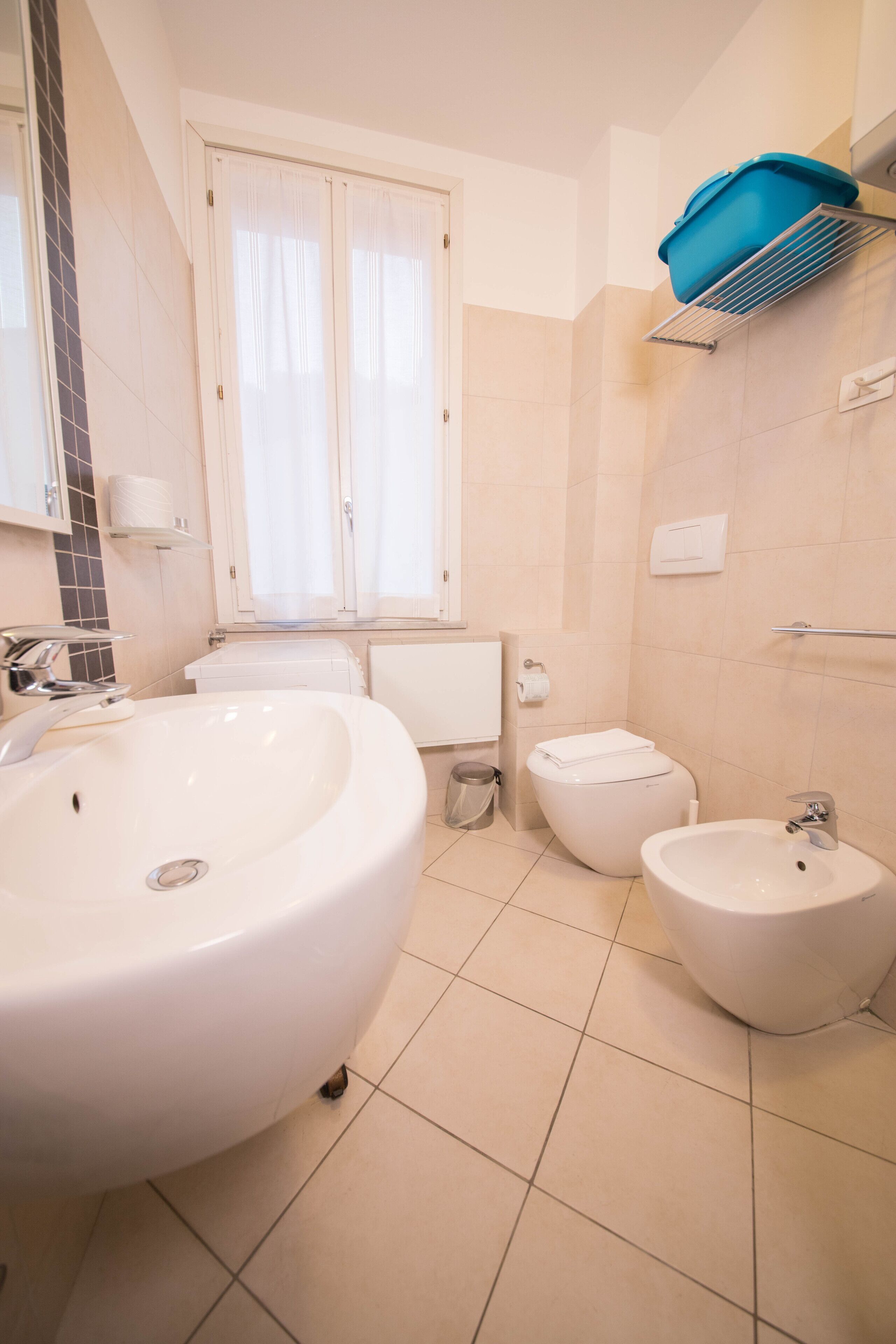 Een badkamer met een groot wastafel, toilet, bidet en een douchegedeelte.