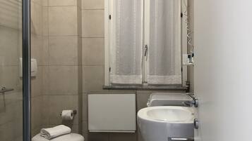 Moderni kylpyhuone, jossa on suihku, bidee, wc ja kaksi pesuallasta.