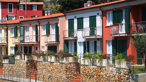 A row of colorful townhouses with green shutters, stone walls, and balconies. - Baia Blu Rta (Lerici)