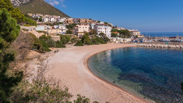 A coastal town with a sandy beach, clear blue waters, and buildings with balconies overlooking the sea. - Casa Collodi (Dorgali)