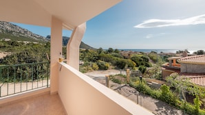 A balcony with a view of a coastal town, greenery, and a mountain in the background. - Villino Panna (Dorgali)