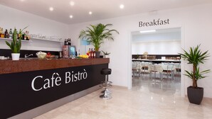 A modern café with a black counter, shelves with bottles, and a breakfast area.
