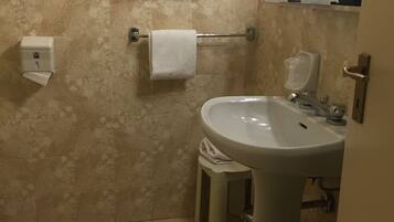 Une salle de bain équipée d’un lavabo, d’un porte-serviettes, d’un sèche-mains et de toilettes.