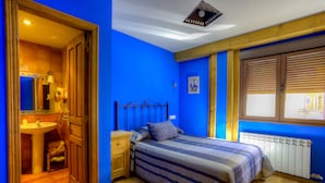A bedroom with a bed, wooden headboard, a nightstand, a dresser, a window with blinds, and a radiator. - La Tintoreria (Villablino)