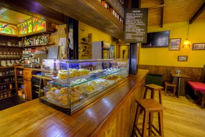 Mostrador de una panadería con diversos productos horneados, una máquina de café y un tablero con la lista de artículos.