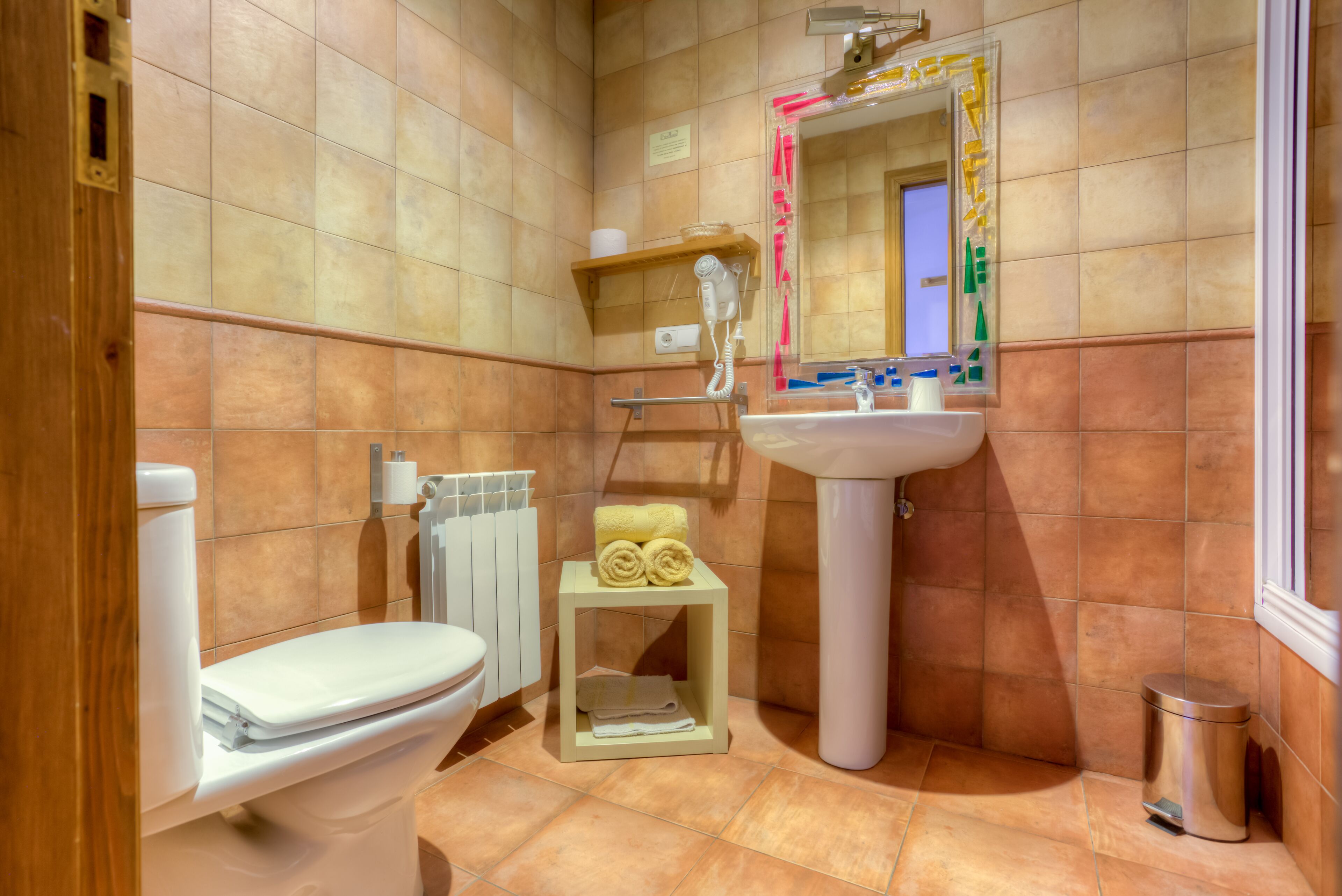 A bathroom with a toilet, sink, and towel storage.