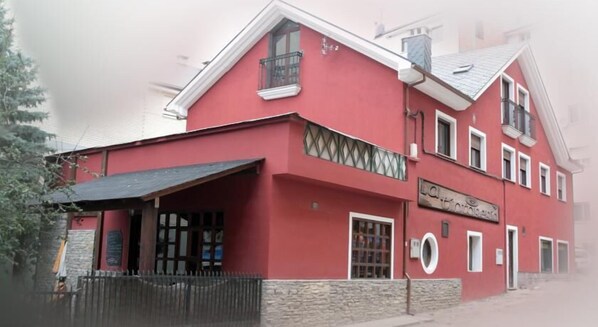 A red building with a balcony and a sign that reads "La Taverna". - La Tintoreria (Villablino)