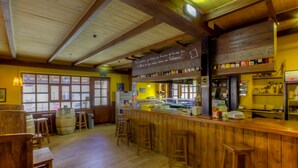 A wooden interior with a bar area, stools, and a windowed wall. - La Tintoreria (Villablino)