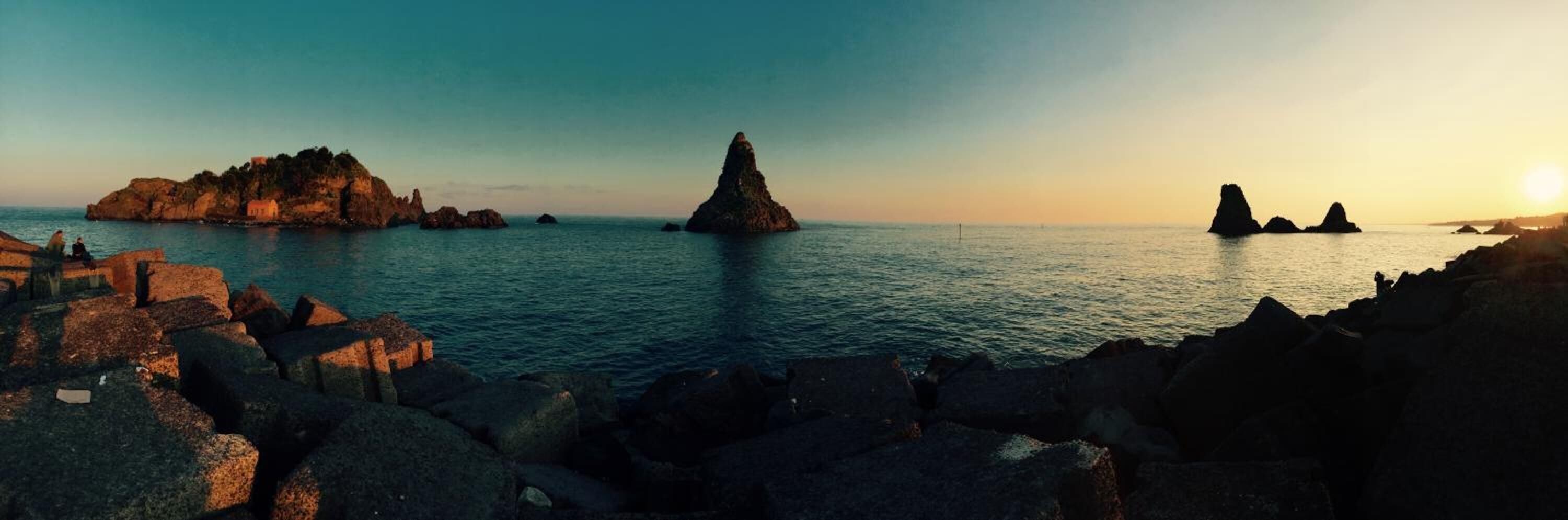 A coastal landscape with rocky formations and calm waters.