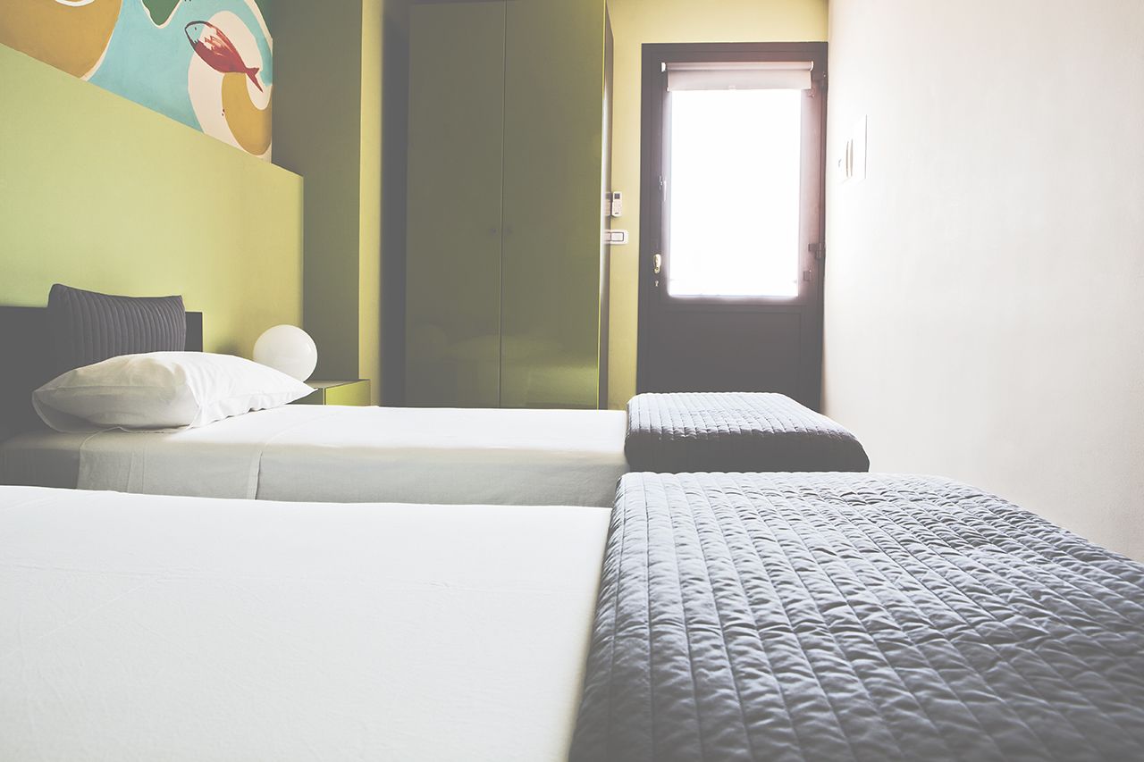 Habitación de hotel con dos camas, una puerta y una pared con un mural de peces de colores.