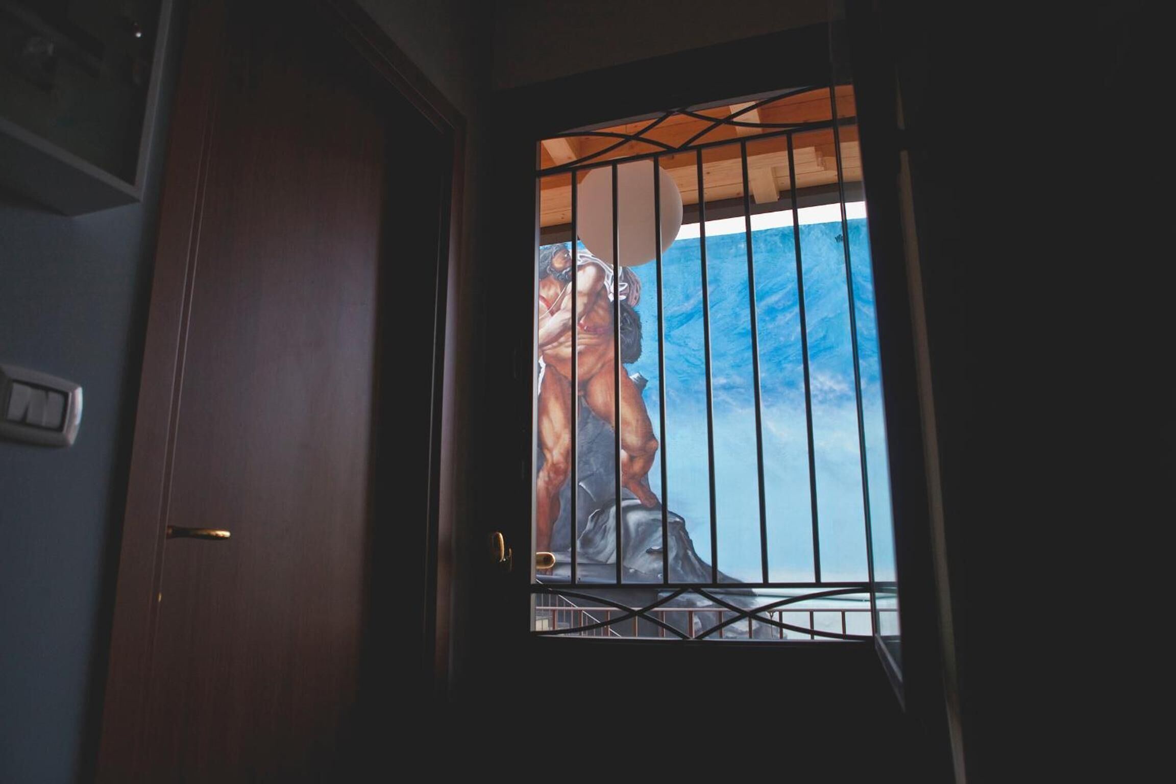 A door with a metal gate and a view of a rocky landscape through the window.