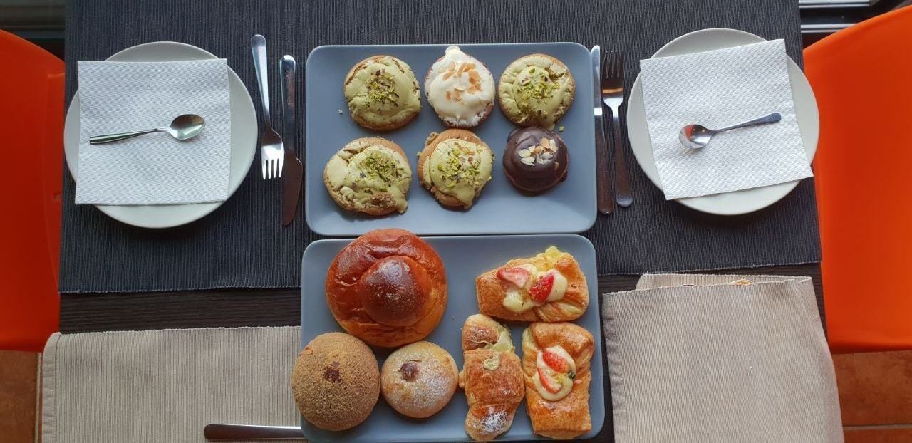 A table with various pastries and bread, arranged on plates and napkins.