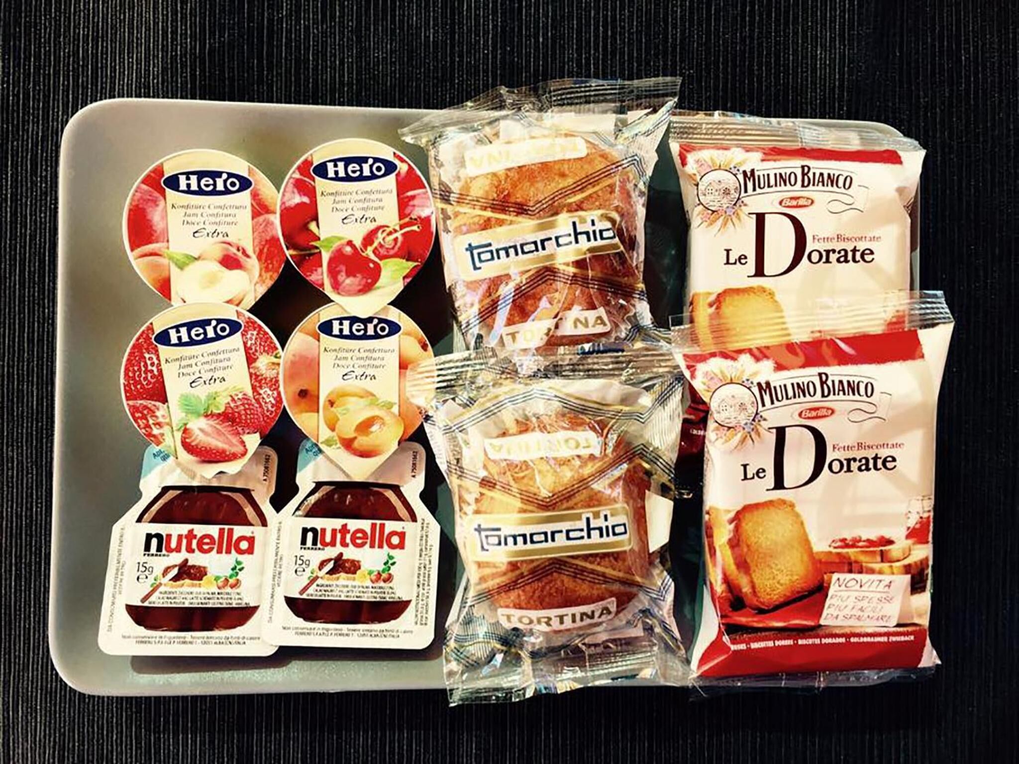 Una bandeja con diversos productos alimenticios envasados, incluyendo Hero, Tomarchio, Le Dorate y Nutella.