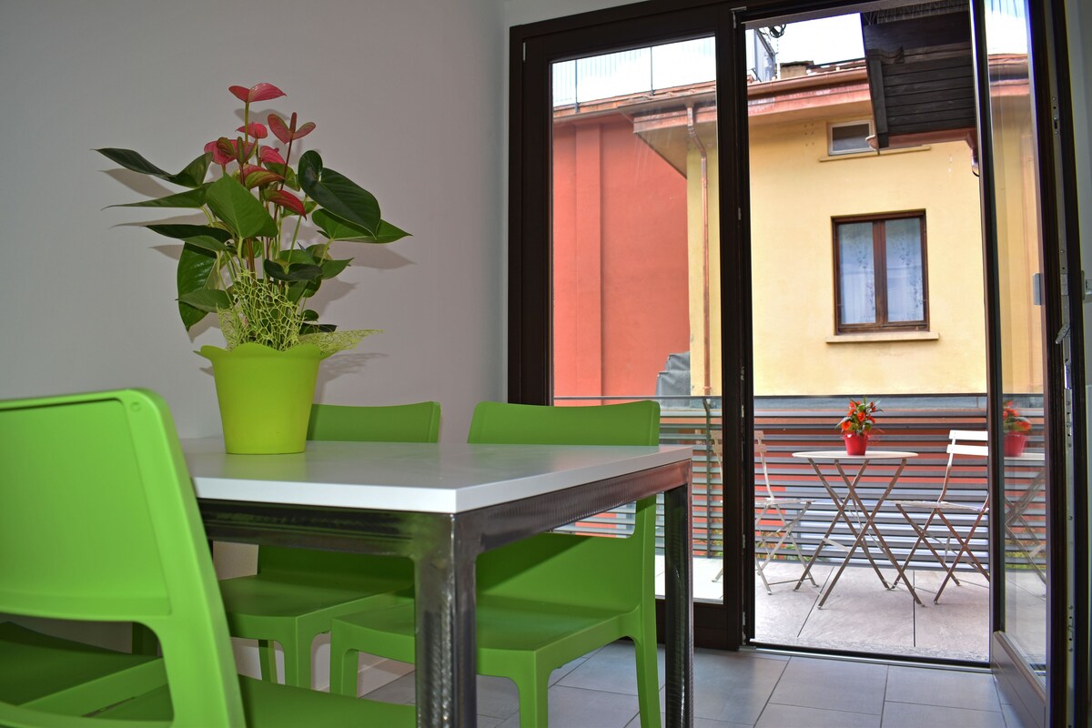 Un coin repas avec une table et des chaises, une plante en pot et une vue sur un balcon également équipé d’une table et de chaises.