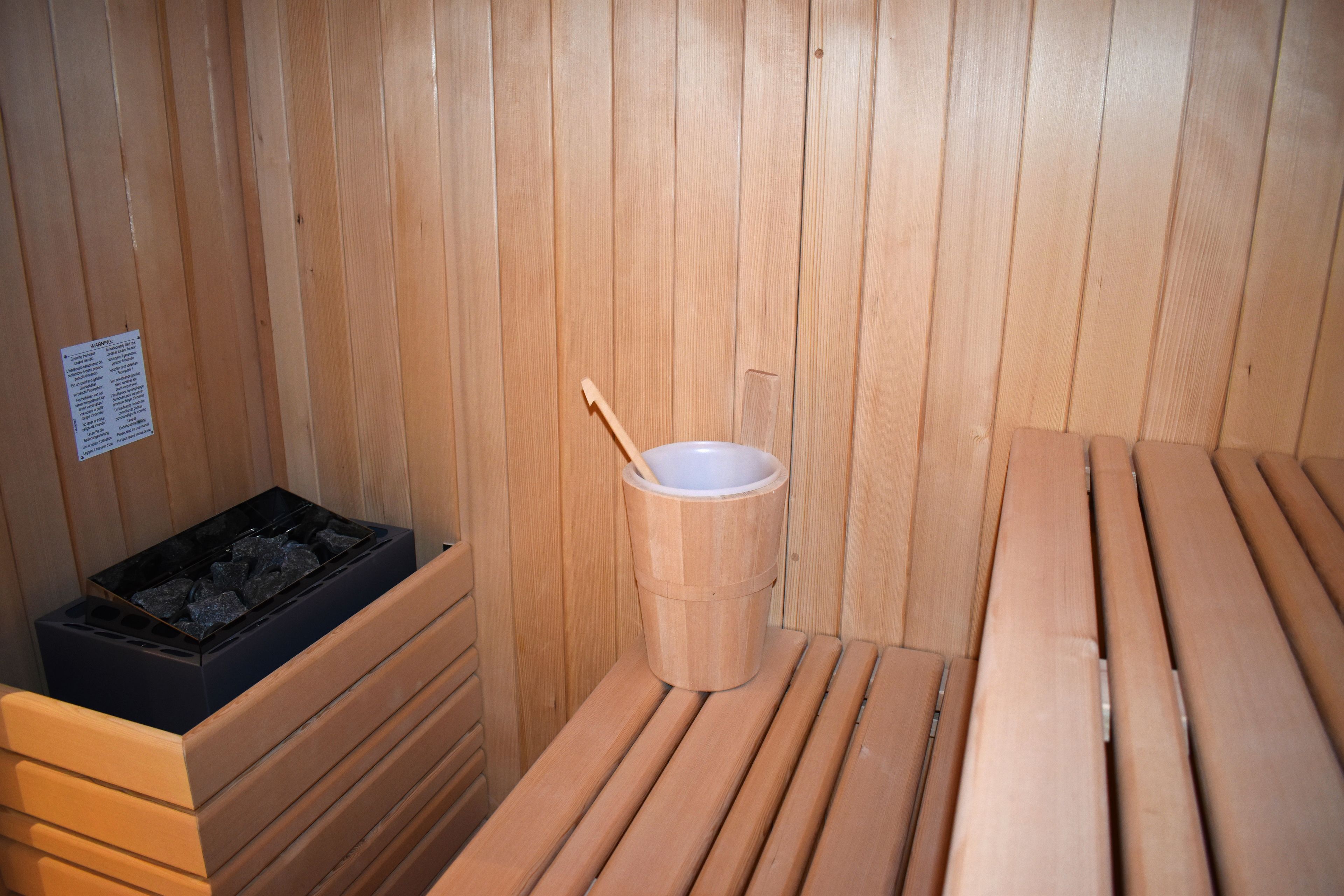 Una sauna de madera con bancos y un cubo.