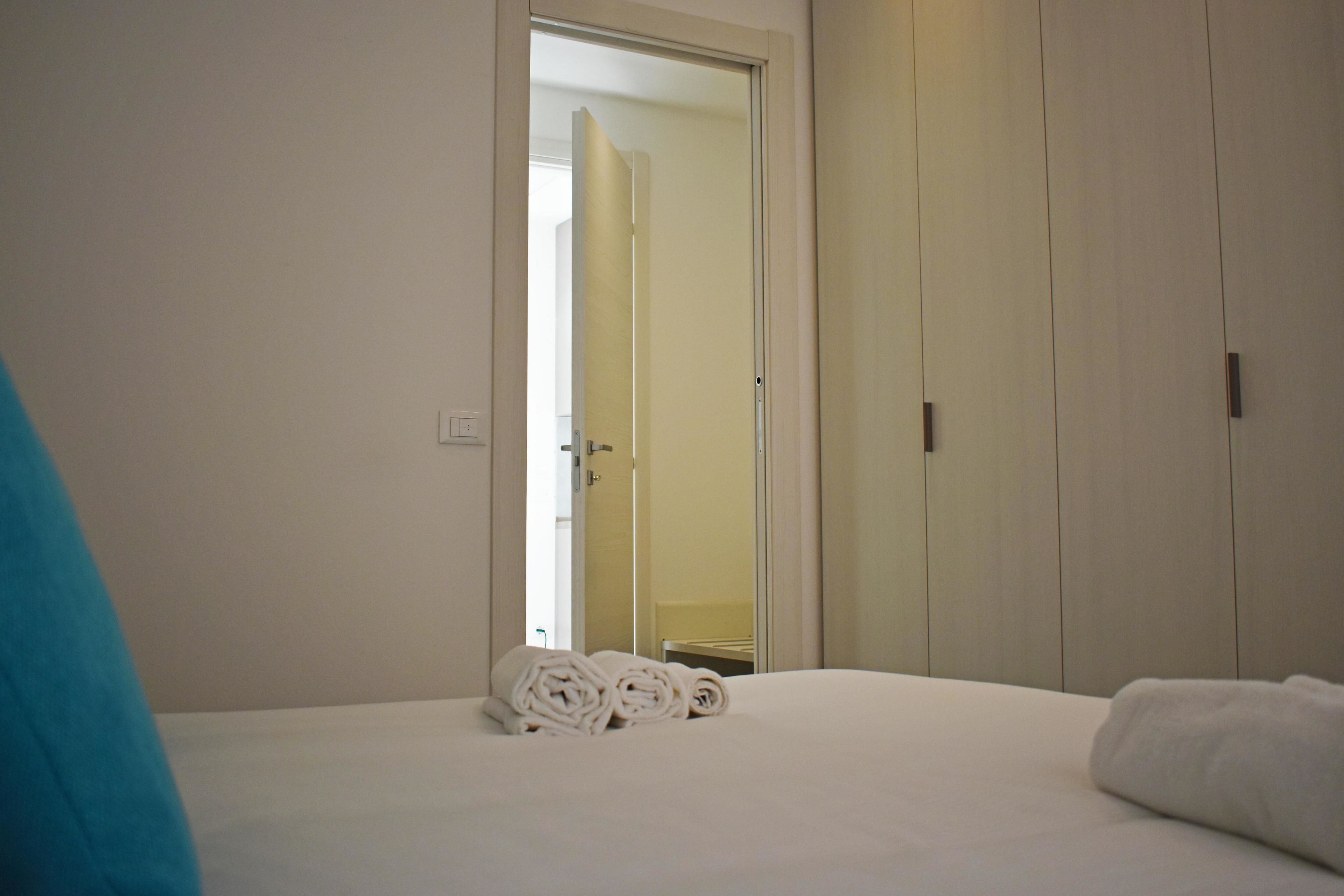 A hotel room with a bed, a mirror, and a wardrobe.