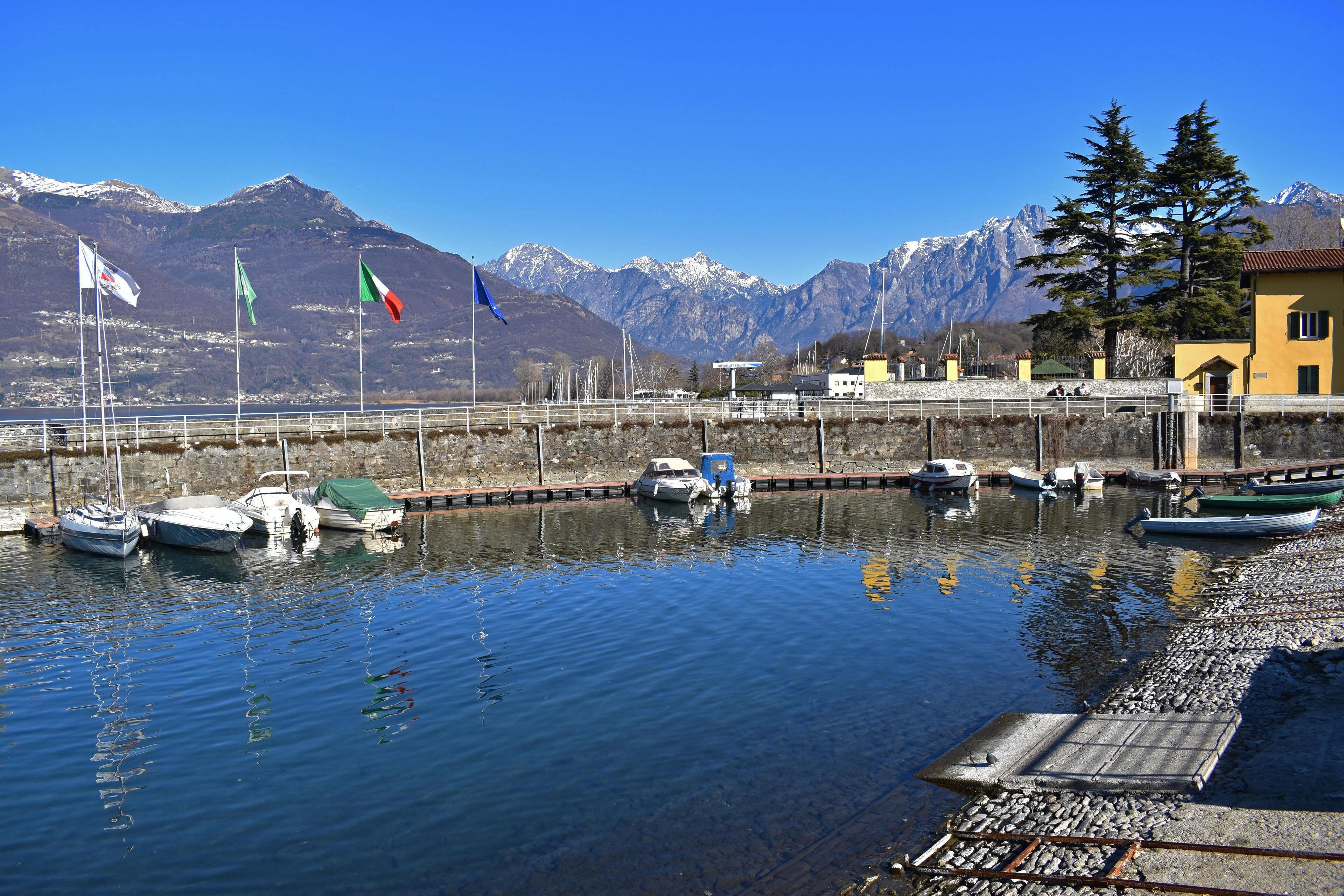 Un port de plaisance avec des bateaux amarrés, un quai et des montagnes en arrière-plan.