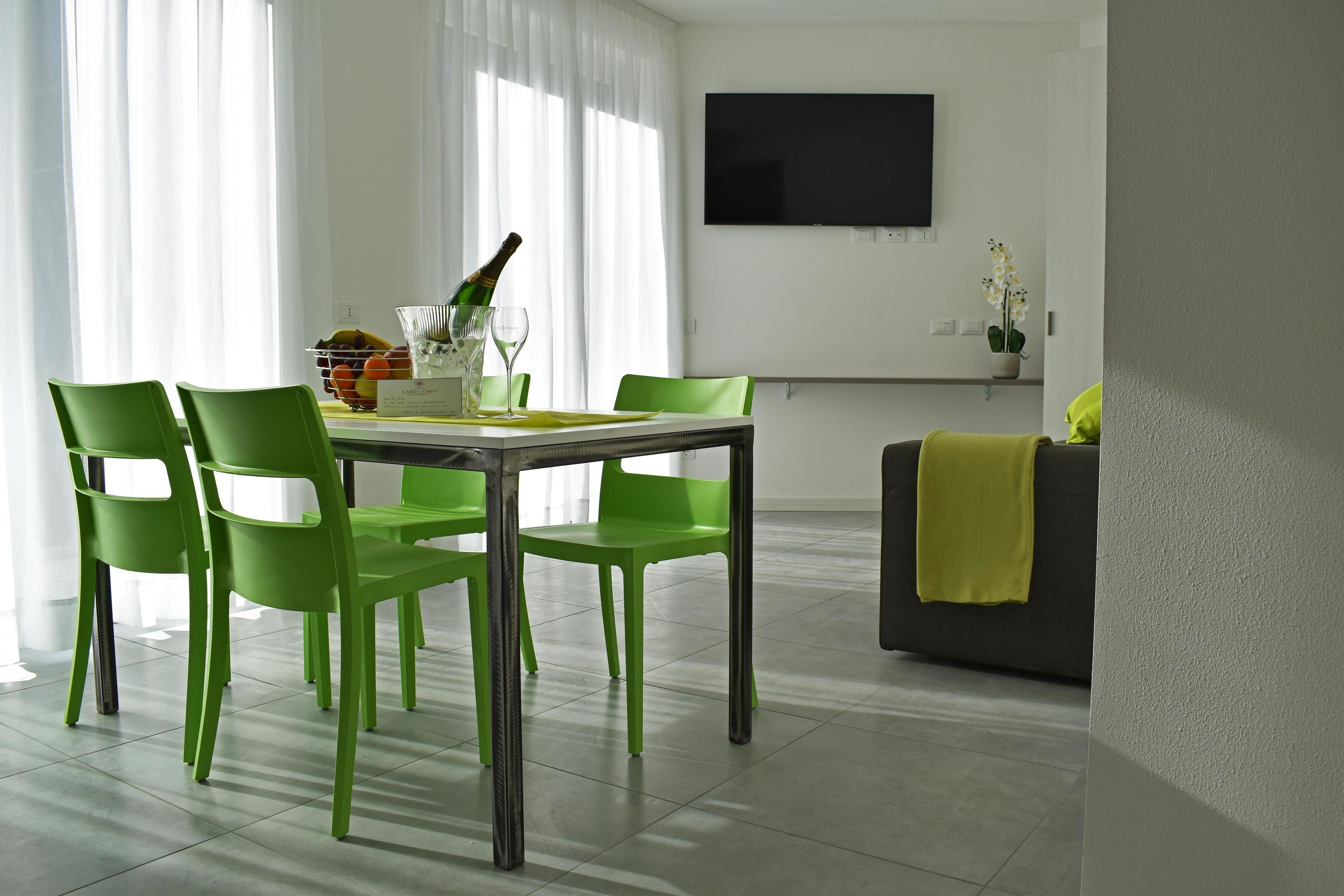 A modern dining area with a table and chairs, a bottle of champagne, and a TV on the wall.