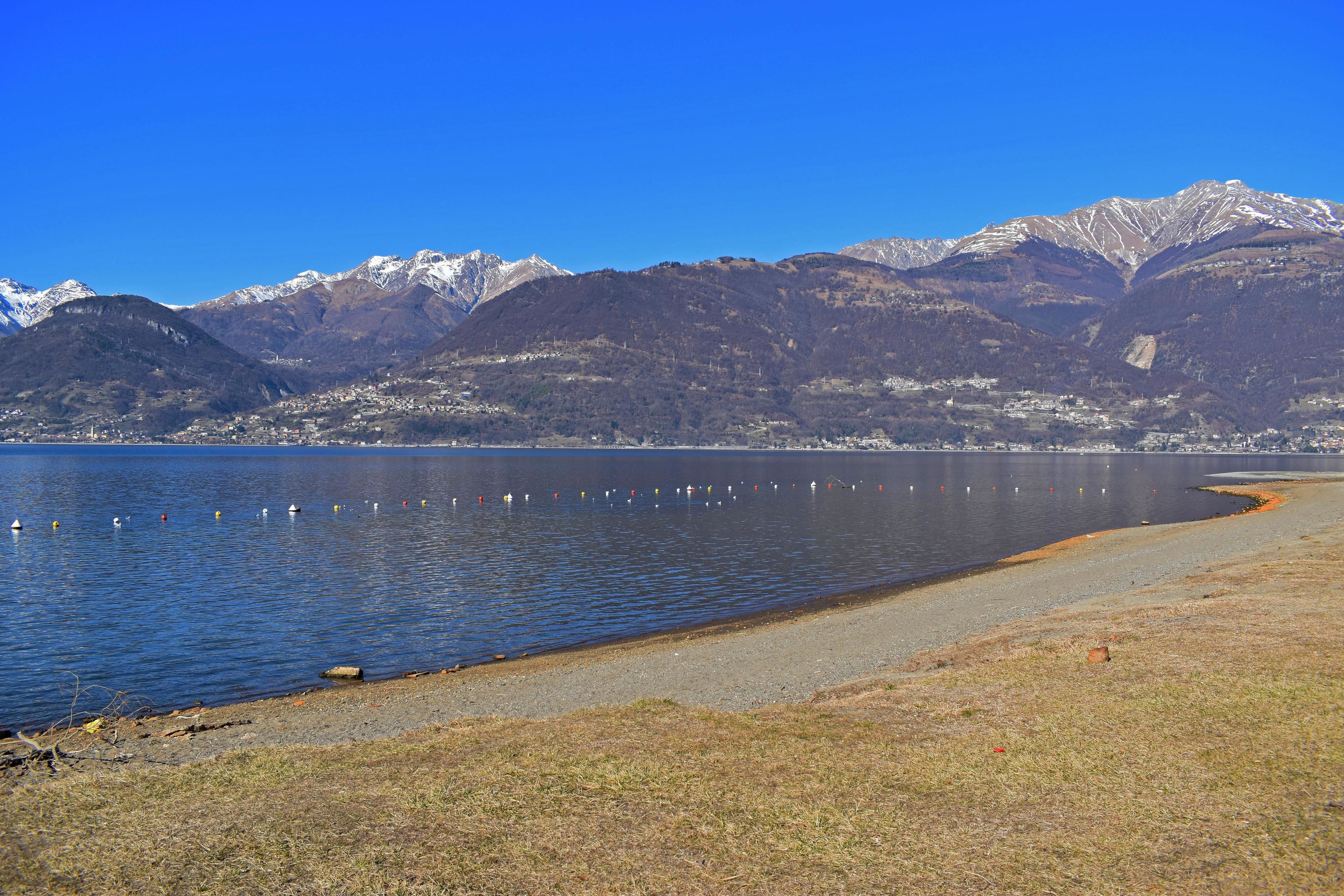 A lakeside view with mountains in the background and a clear sky.