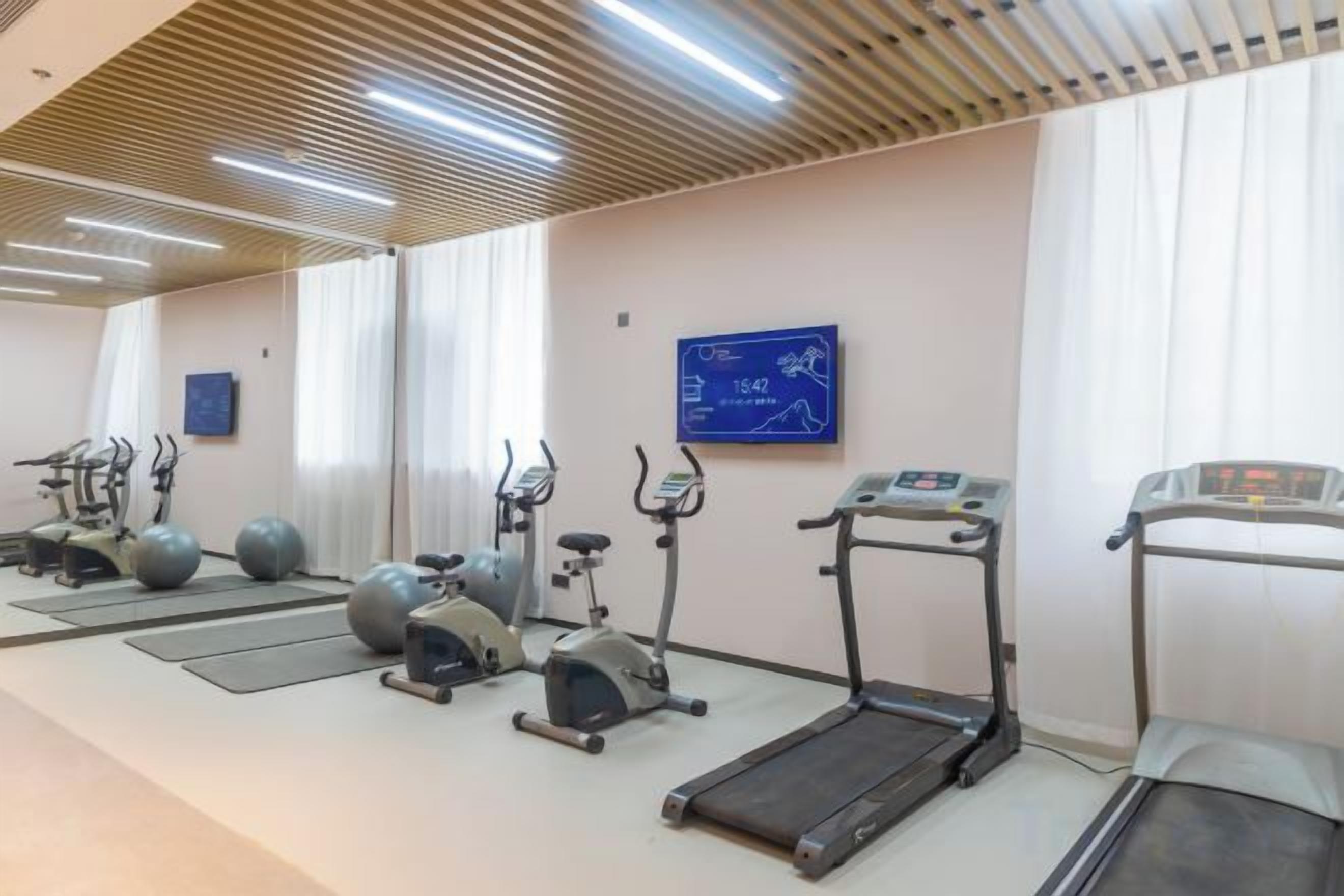 A gym with treadmills, stationary bikes, and exercise balls.