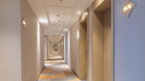 A hotel corridor with a checkered floor pattern, a series of doors on the right, and a sign with the number 8616 on the wall. - Jinjiang Inn (Tianshui)