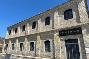 Un edificio de piedra histórico con múltiples ventanas y un letrero en un idioma extranjero.