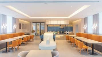 A modern dining area with tables and chairs, a central counter, and a kitchen in the background.