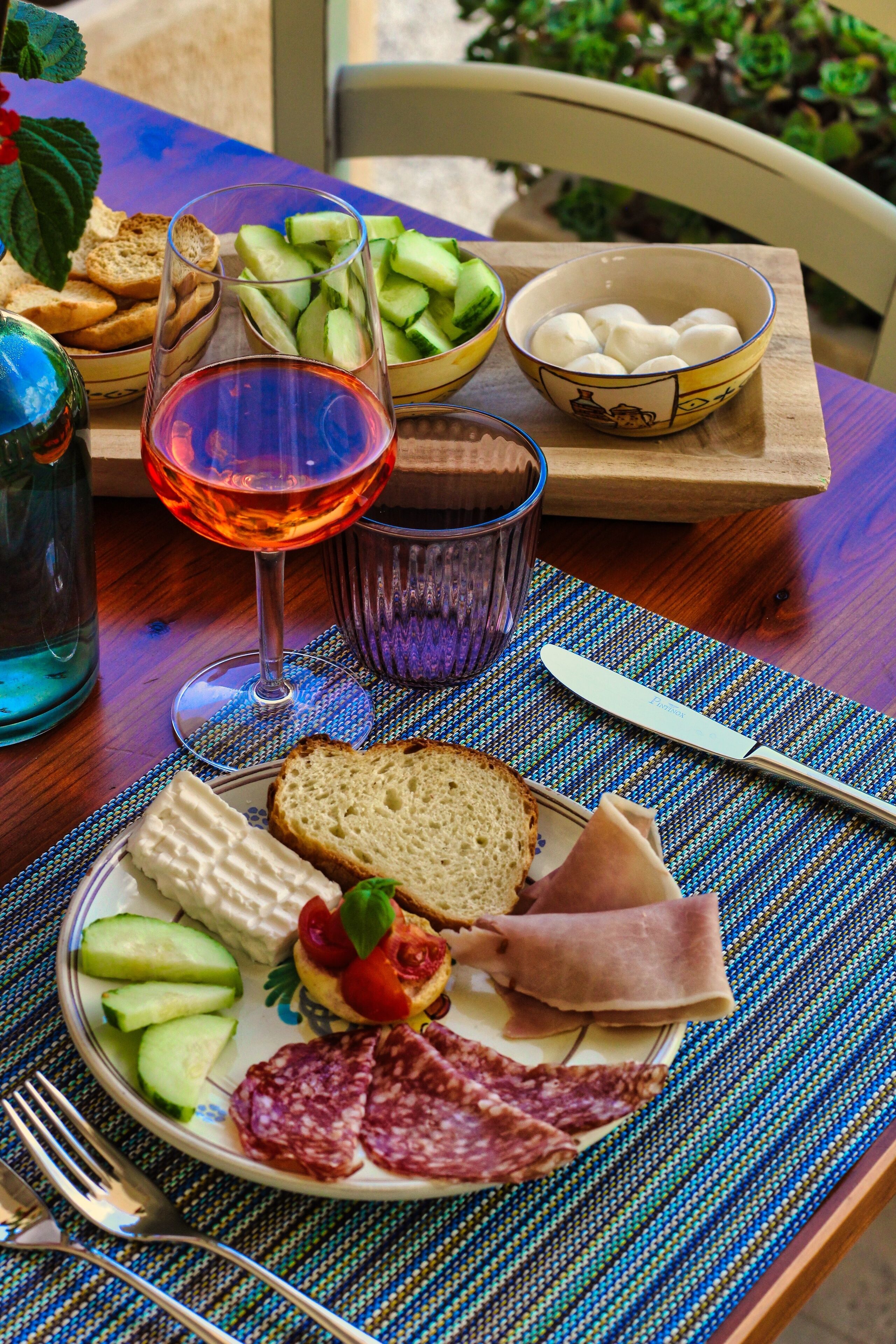 Un tavolo con un piatto di cibo, un bicchiere di vino rosso e una ciotola di formaggio.