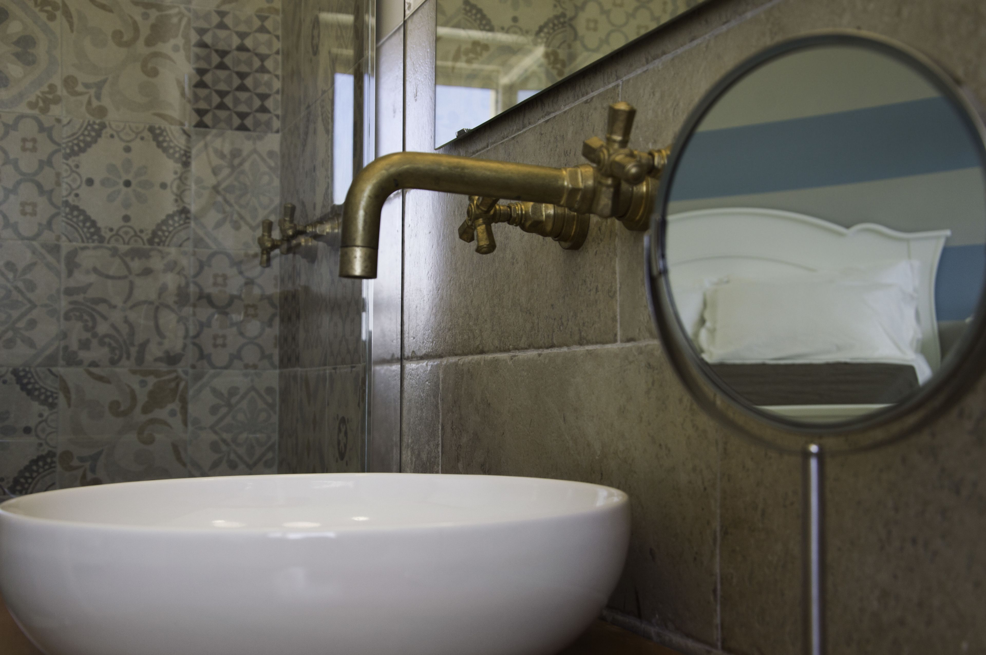A bathroom with a white sink, a brass faucet, and a mirror.
