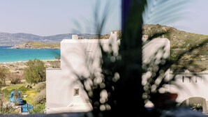 Vista costera amb un edifici blanc, un cotxe blau i un mar blau clar.