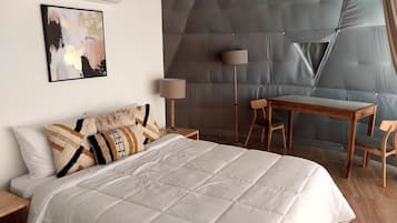 A modern hotel room with a large bed, a desk, and a chair.