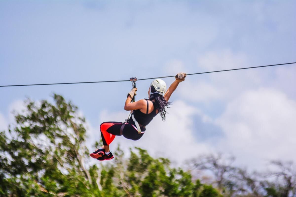 A person zip-lining with a harness and helmet, holding onto a cable.