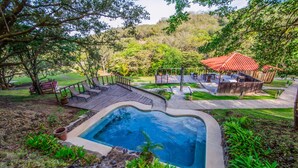 A pool area with a wooden deck, a small pool, and a covered seating area with a red roof. - Vida Aventura Ranch (Mogote de Bagaces)