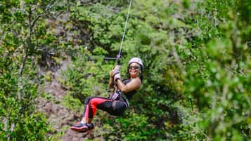 Uma pessoa a fazer zipline por uma área arborizada.