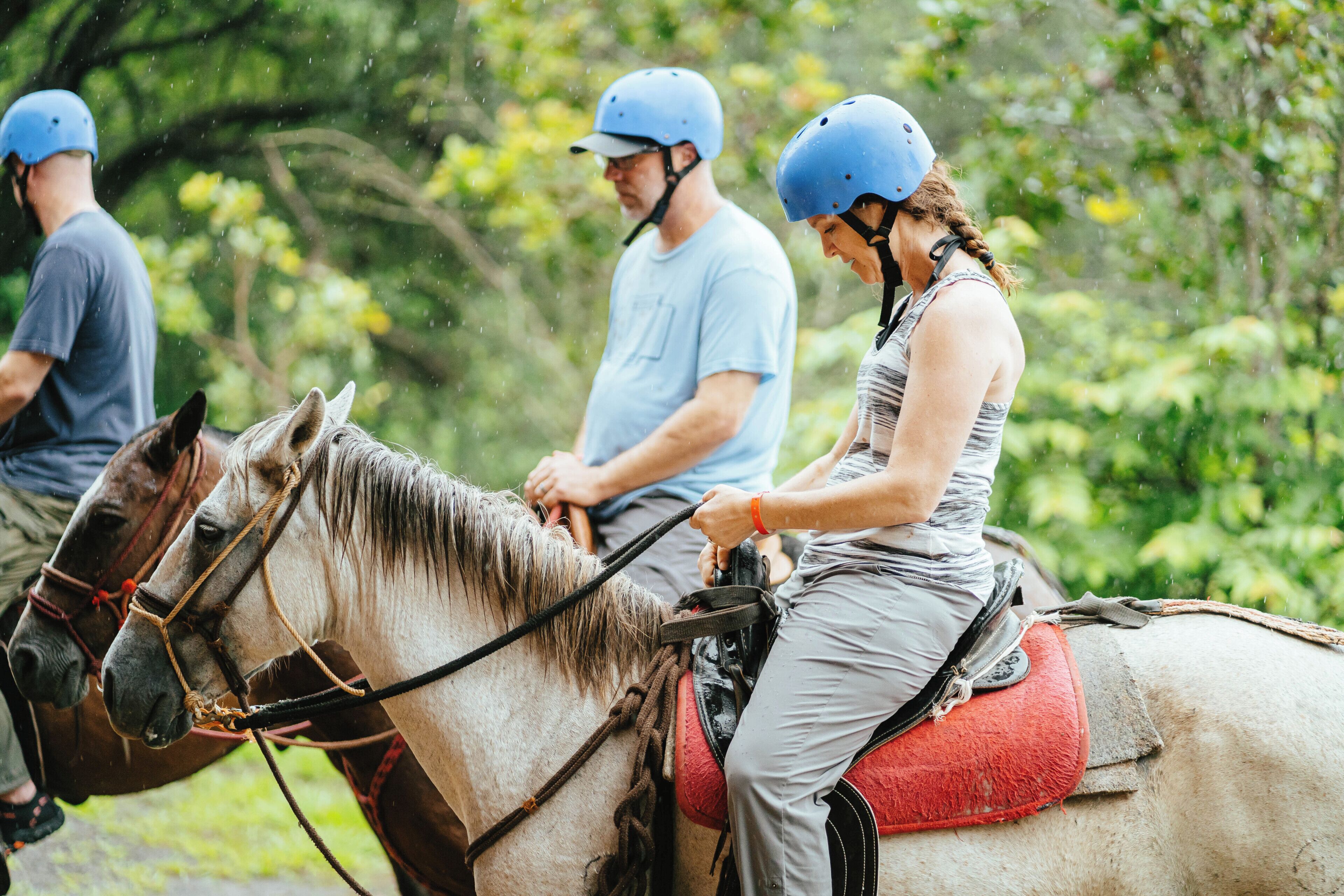 Three people riding horses in a natural setting.