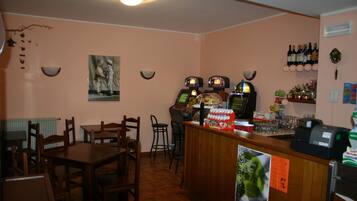 Ein Restaurantinneres mit Holztischen und -stühlen, einer Bar mit Kasse und Weinschränken an der Wand.