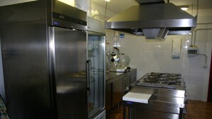 A kitchen with stainless steel appliances, including a refrigerator and a stove. - Albergo Alle Alpi (Comeglians)