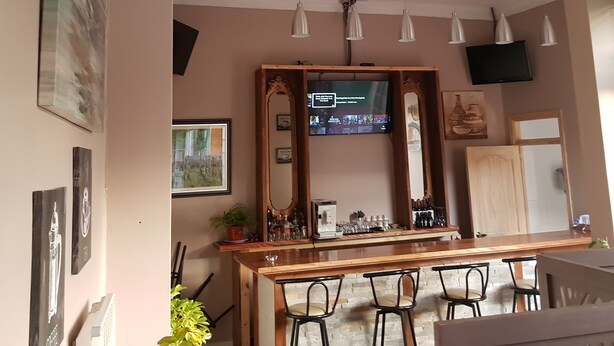 Una zona de bar con una barra de madera, taburetes y un televisor colgado sobre la barra.