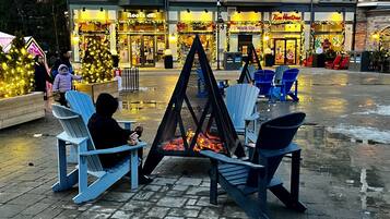 Une place publique avec un foyer et des fauteuils Adirondack.