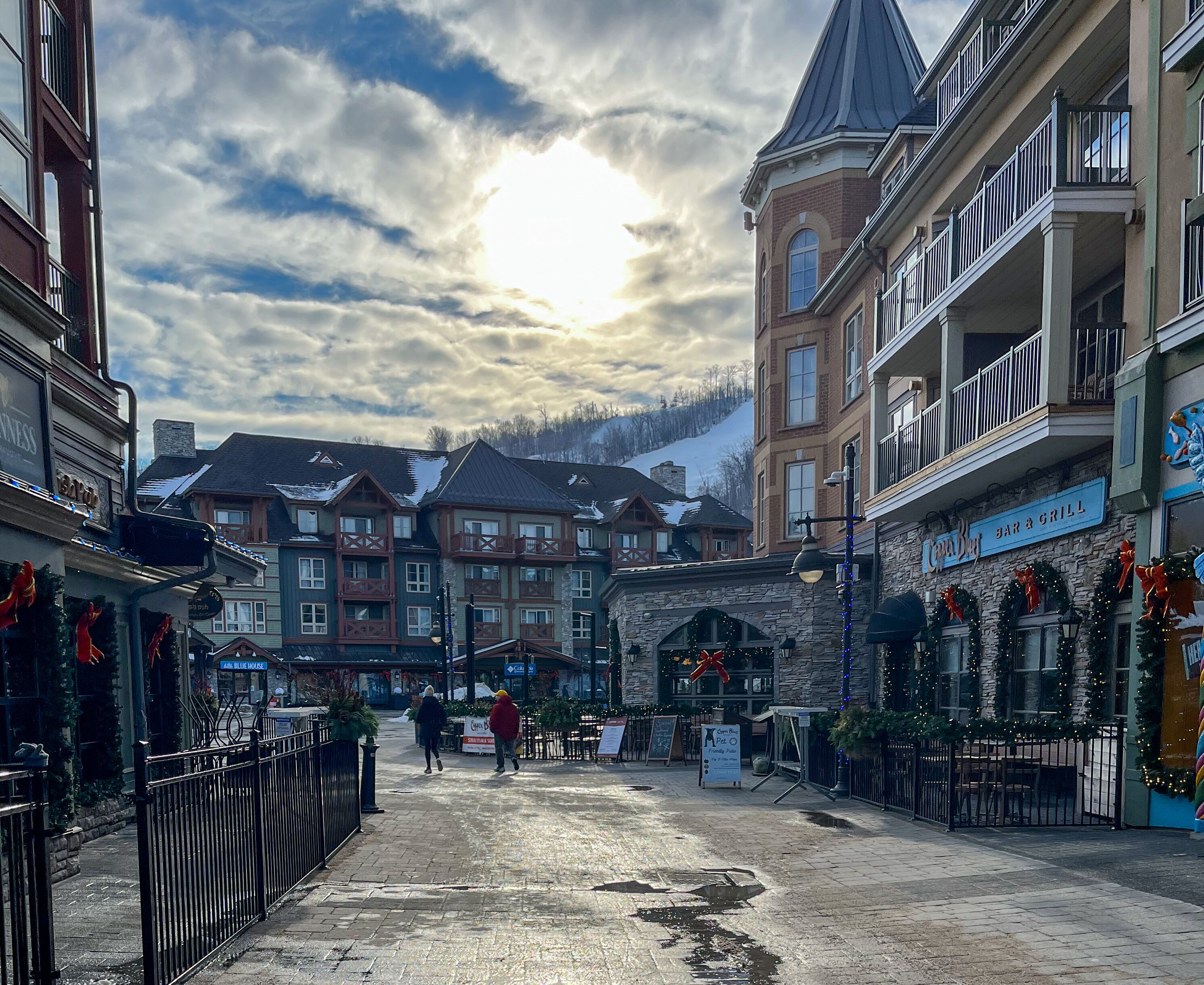 A town square with buildings, a sign for a bar and grill, and a clear sky.
