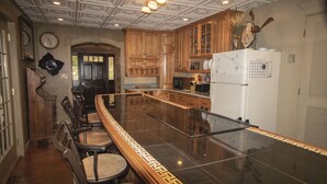 A kitchen with wooden cabinets, a refrigerator, and a bar area with chairs. - Ledges by GetAway (Bridgewater Corners)