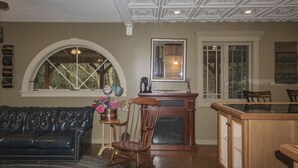 A living room with a dark leather sofa, a wooden chair, a fireplace, and a dining area with a glass-top table. - Ledges by GetAway (Bridgewater Corners)
