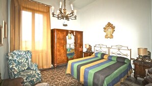 A hotel room with a bed, a chair, a wardrobe, a chandelier, and a wall-mounted picture. - SIENA MEDIEVALE - Three Bedroom Apartment, Sleeps 6 (Siena)